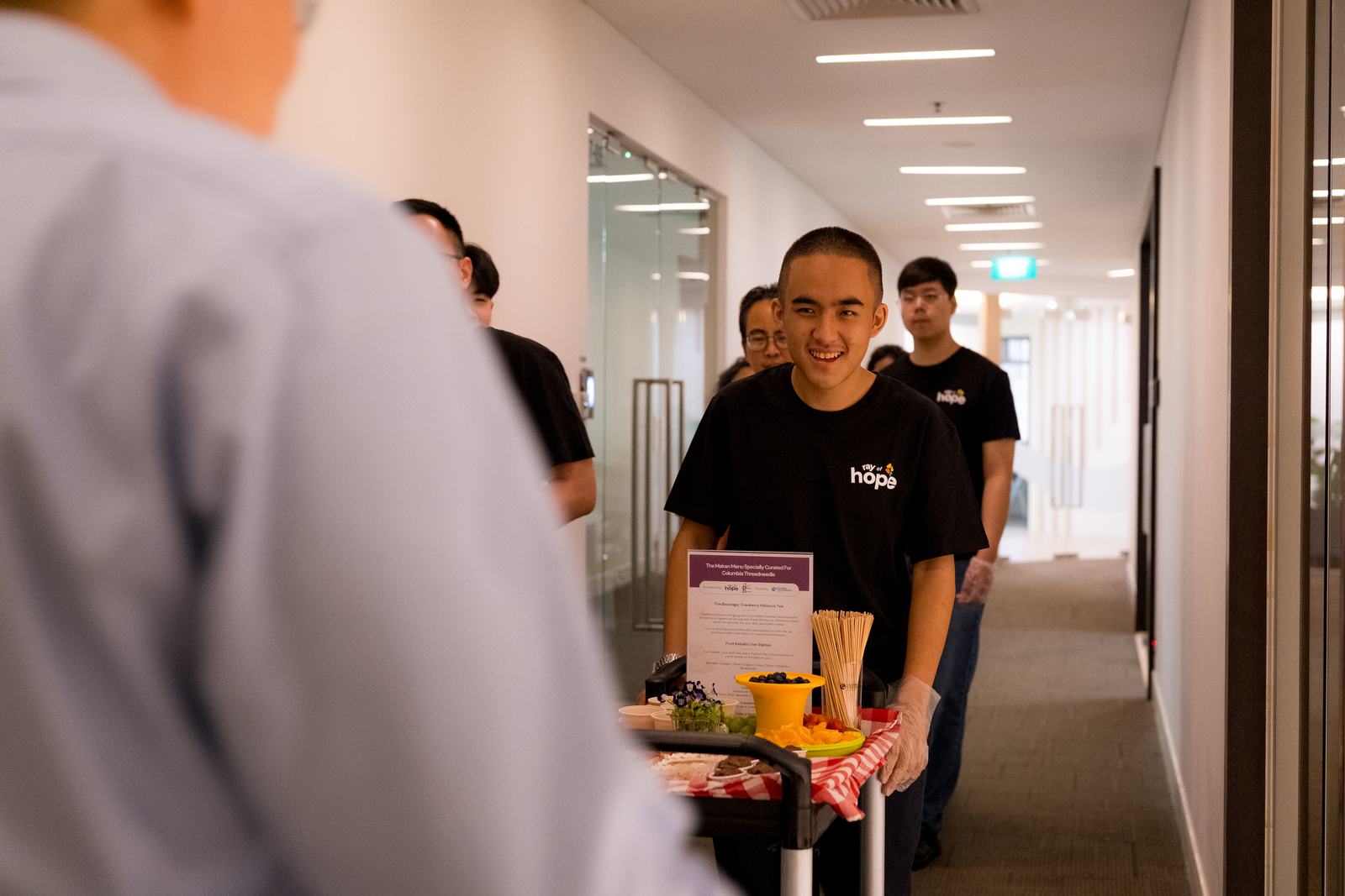 A KTM youth wheeling a snack cart through an office